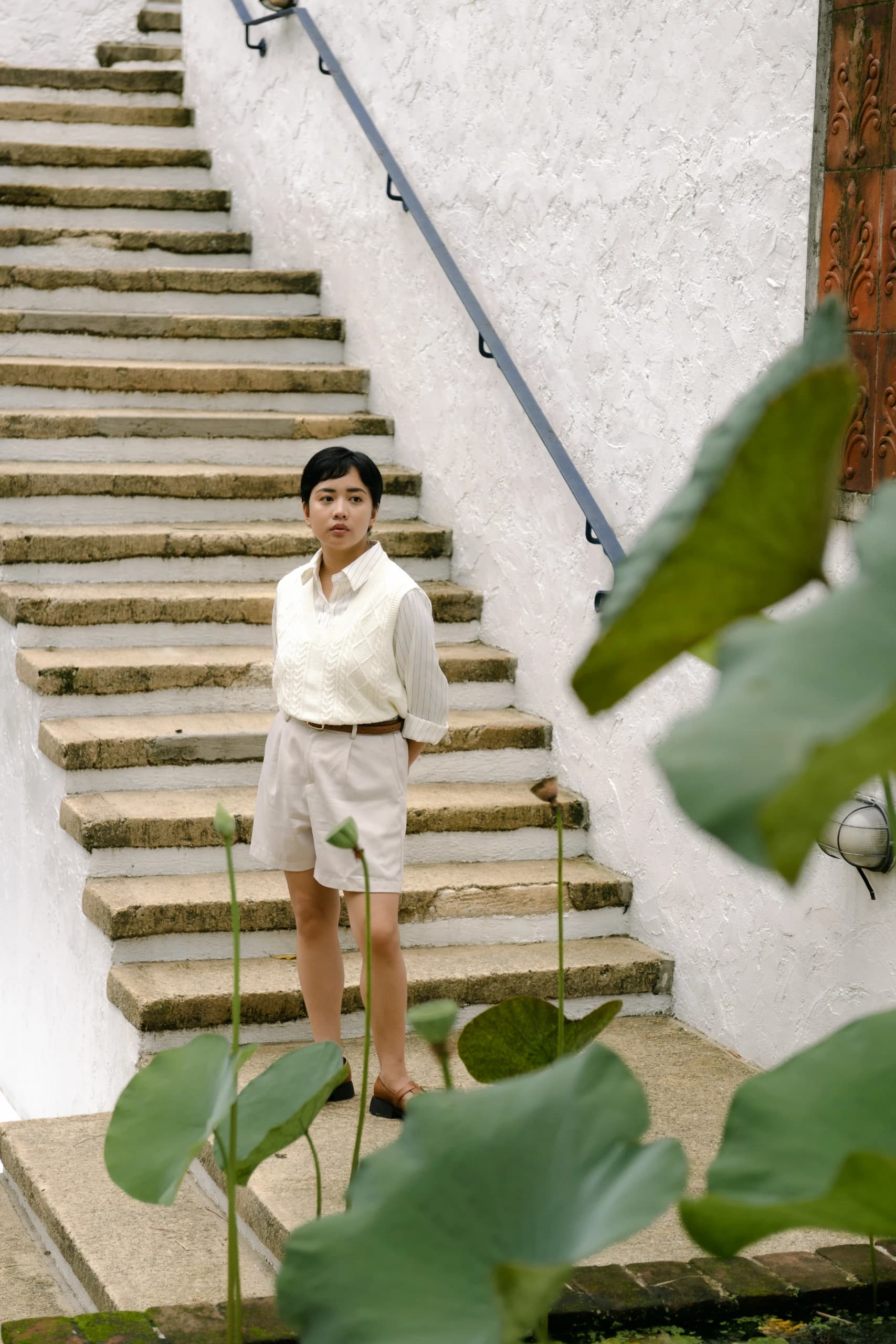 Stefie and Kenn outside the house — she against the breeze-block wall, he on the step beside it.